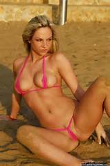 sand covered Ambra sitting on the beach in a red string bikini